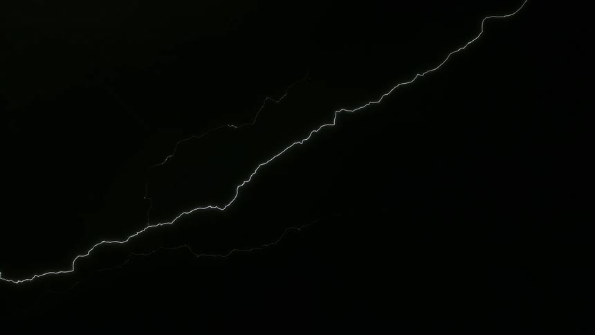 A jagged lightning bolt during a storm against a dark sky shooting upwards into the night