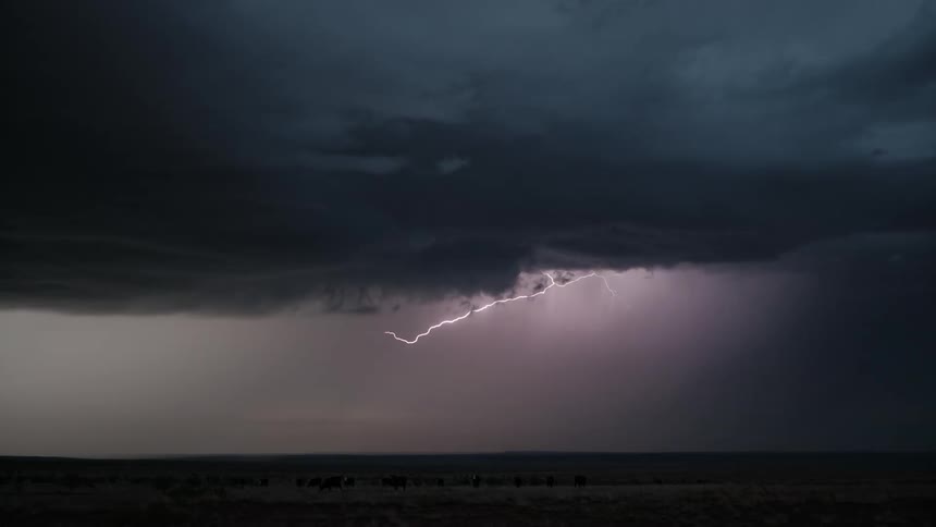 Landscape of a greenish field against a sky with lightning