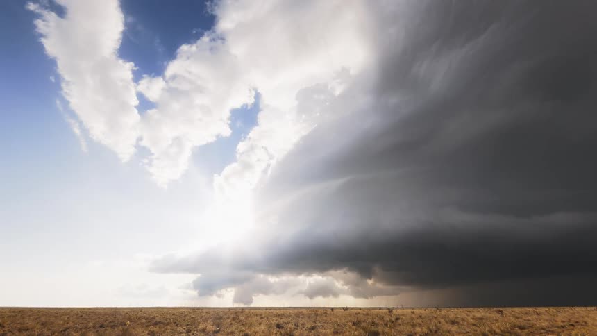 A time lapse of dark sprawling storm clouds rolling over a vast landscape