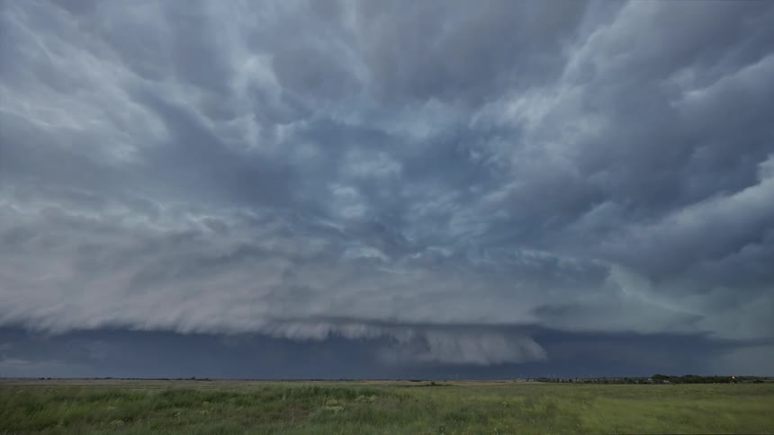 A time lapse of dark sprawling storm clouds rolling over a vast landscape
