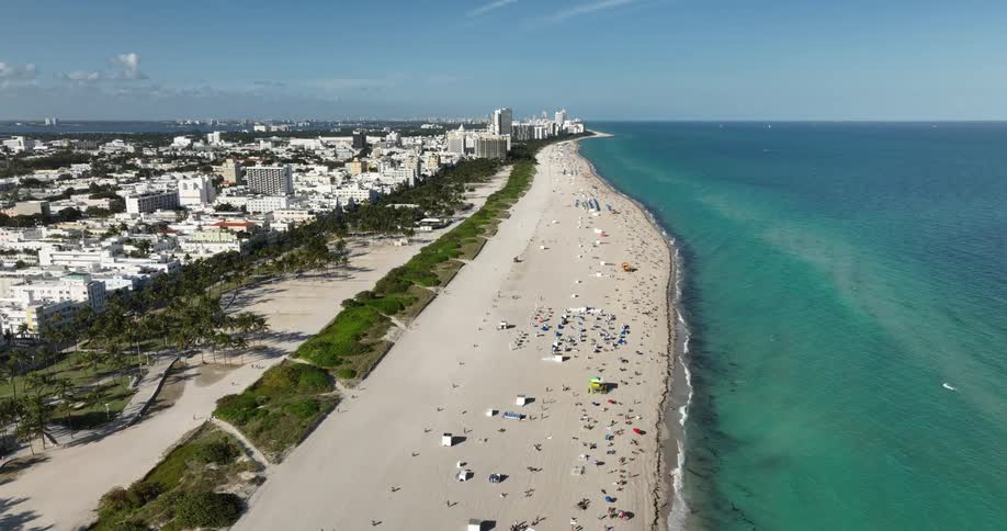 People crowd a beach near a large city area