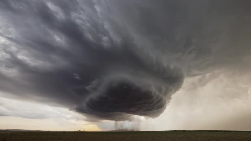 A huge black storm cloud in a sky in a flat region