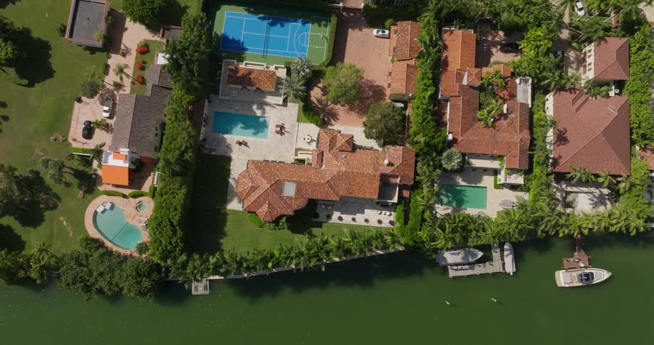 Aerial view of highend houses with swimming pools and the edge of a greenish lake