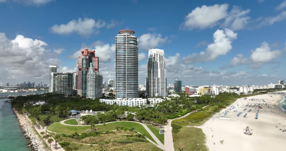 A metropolitan city with very tall buildings and there is a beach next to it with lots of people and buildings in the sand