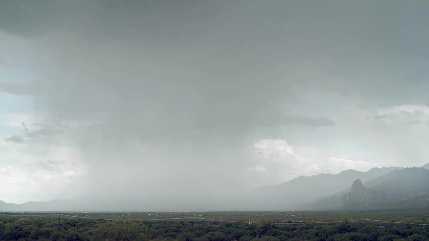 Multiple lightning bolts strike the ground between a rural town and the nearby mountains during a thunderstorm