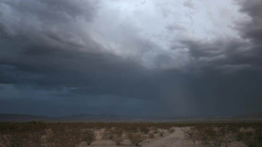 A large thunderstorm drops lightening over mountains and a desert