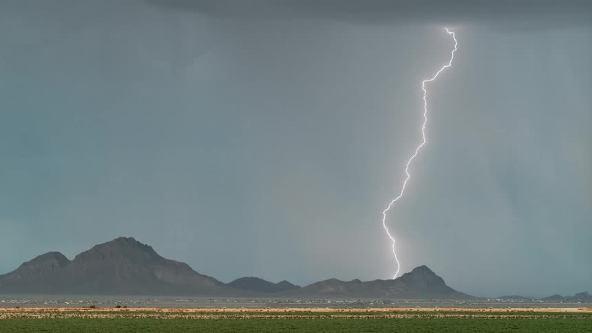 Storm with bright lightning above a field with mountains