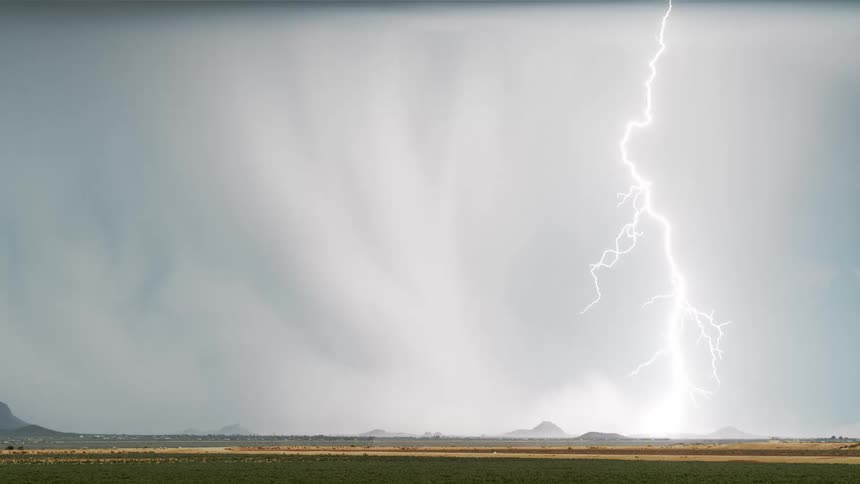 Scenery of a natural grass field and a sky with storm and lightning that shines