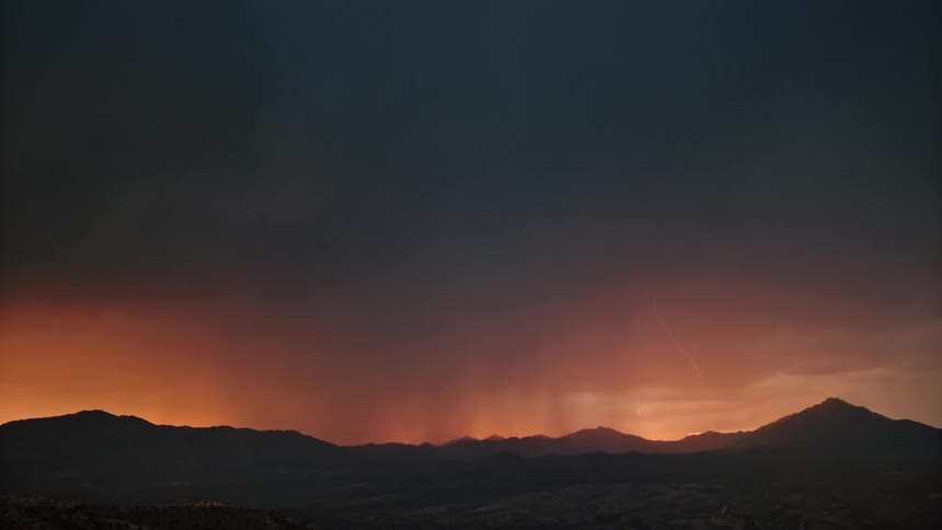 Silhouette scenery of mountains in a reddish sky with thunder storm