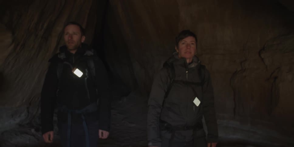 Man and woman walking out of a dark cave