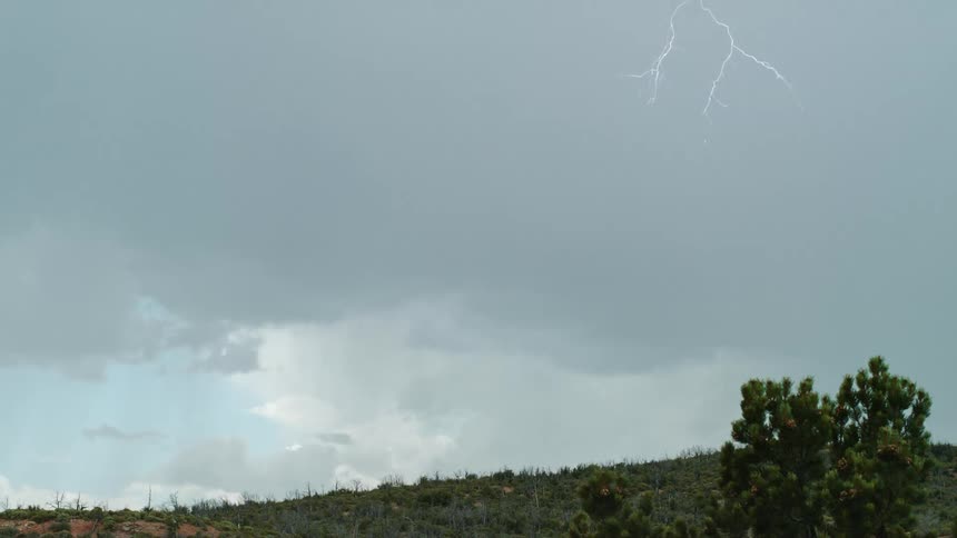 Several bolts of lightning descend from gray storm clouds up above
