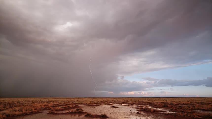 A dramatic thunderstorm with lightning strikes the plains in daylight
