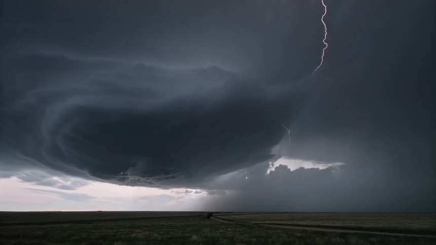 Storm with dark sky bursts of lightning above a greenish field