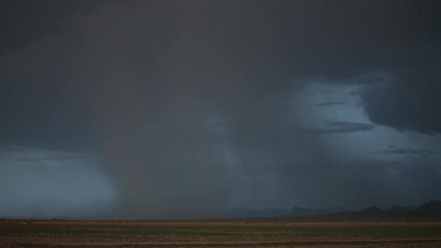 A lightning strike pierces through dark stormy skies illuminating the landscape below