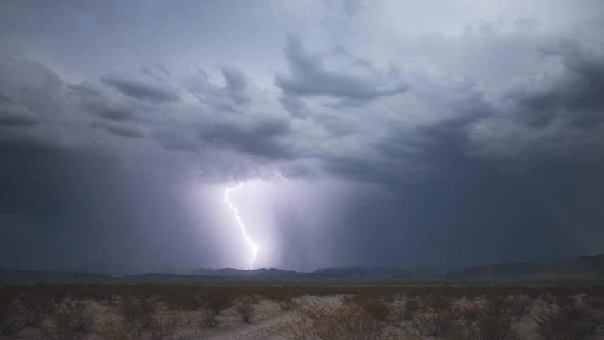 Storm clouds drop enormous lightening strikes on the horizon
