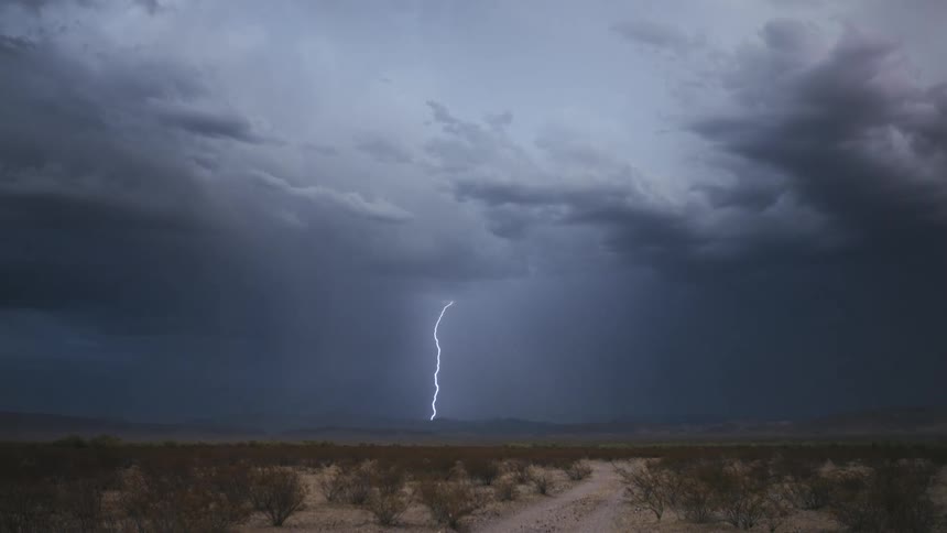 A lightning storm coming out of a large gray cloud in the sky