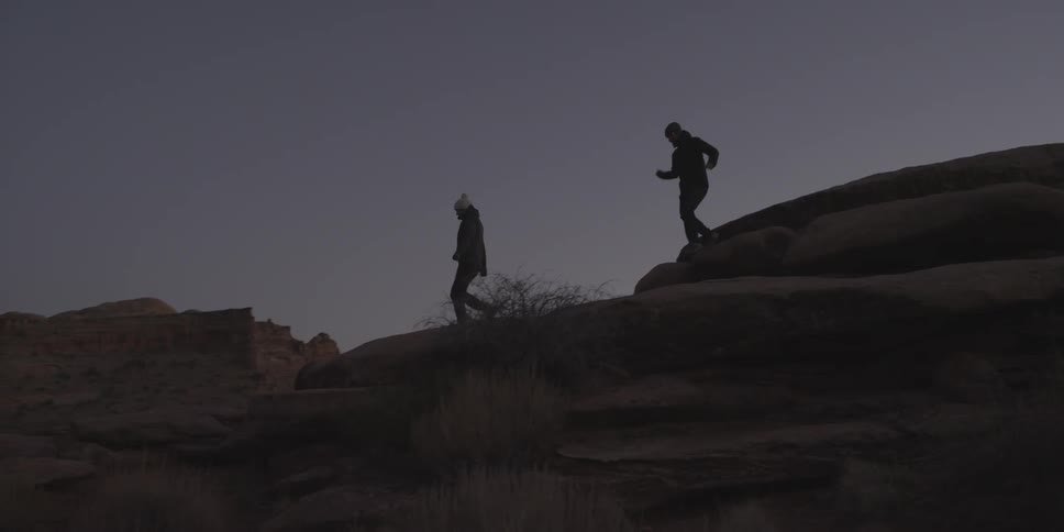 Couple traversing a rocky terrain as the night is setting in