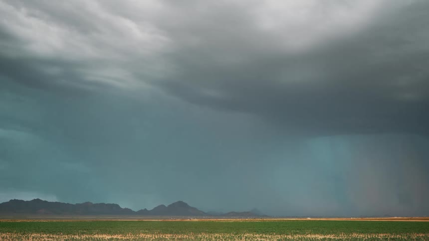 A powerful bolt of lightning strikes down from a stormy sky over a distant mountain range