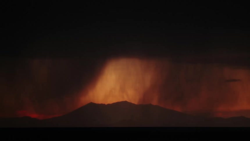 A lightning strike pierces through dark stormy skies illuminating the landscape below