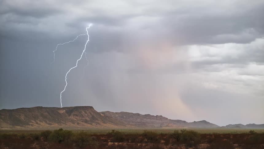 Storm with thunder above mountains in a field