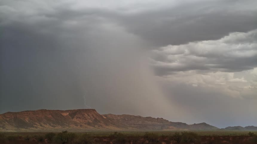 Storm clouds loom overhead and lightning bolts strike the landscape below