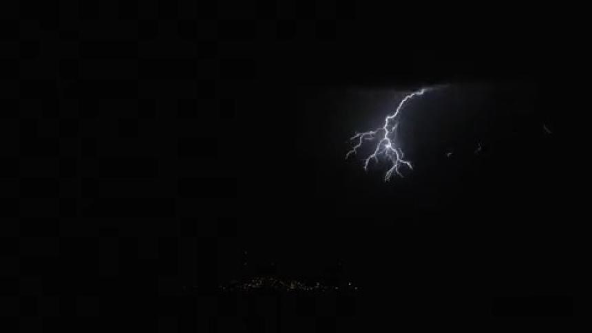 Lightning strikes the ground casting towers into silhouette during an evening thunderstorm