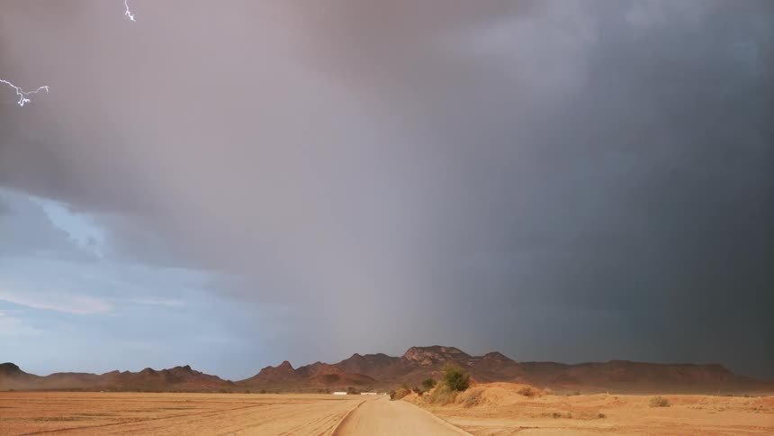 A dramatic thunderstorm with lightning strikes in the desert at daytime