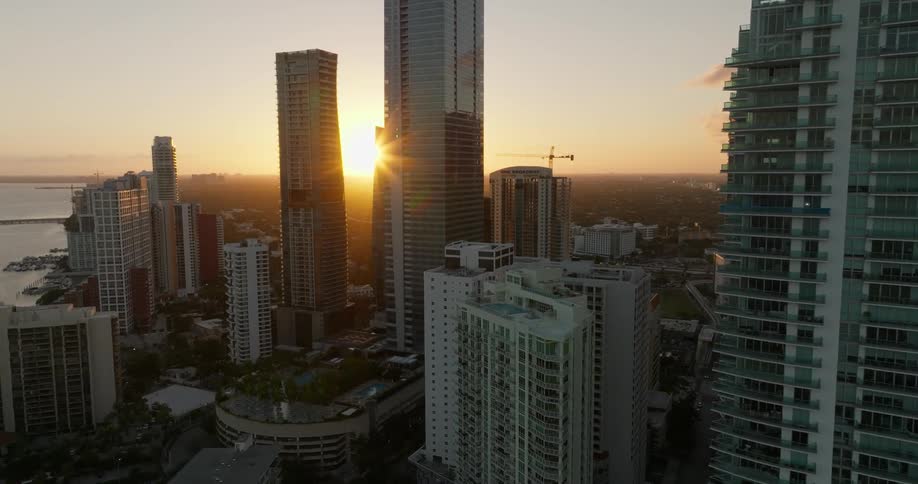 Aerial view of buildings and skyscrapers in a metropolis with a sunset on the horizon