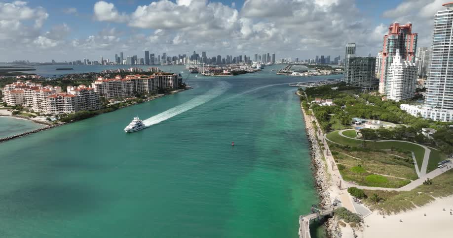 A coastal cityscape with highrise buildings along the shore a clear blue river flowing into the sea