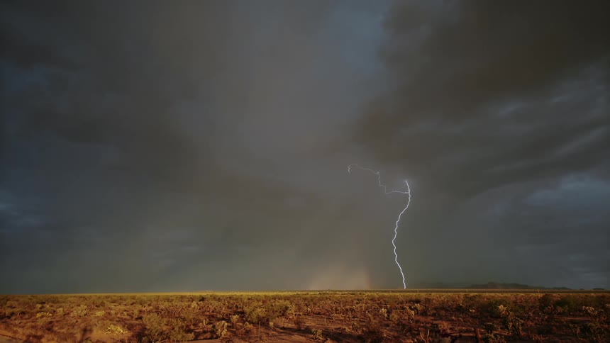 Dry field against a cloudy sky with lightning