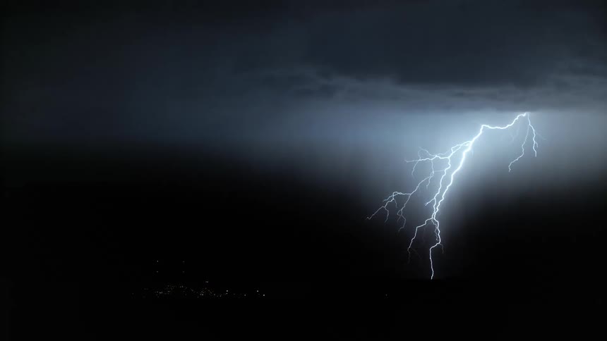 Lightning bolts illuminate towers during a thunderstorm at night