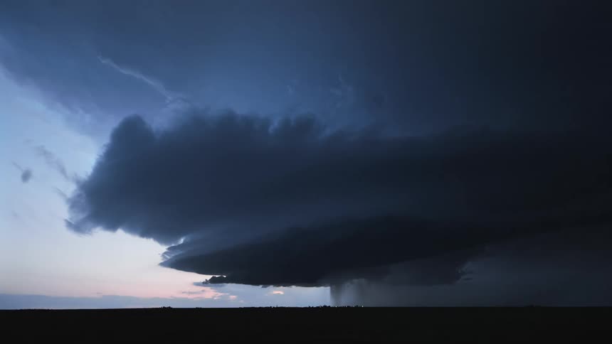 Heavy dark clouds hang over the field as lightning flashes at dusk