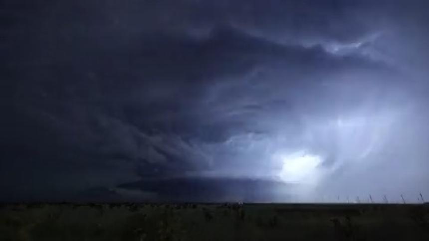 Multiple lightning strikes illuminate the sky inside dark storm clouds over the plains