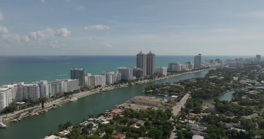 A channel runs between big city buildings on a beach area and suburbs