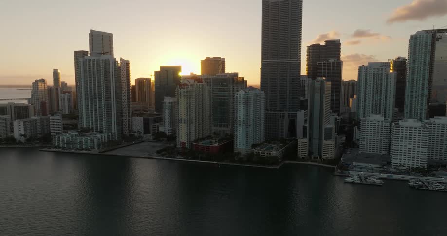 Sun rises from the horizon to peak over downtown skyscrapers near the waterfront