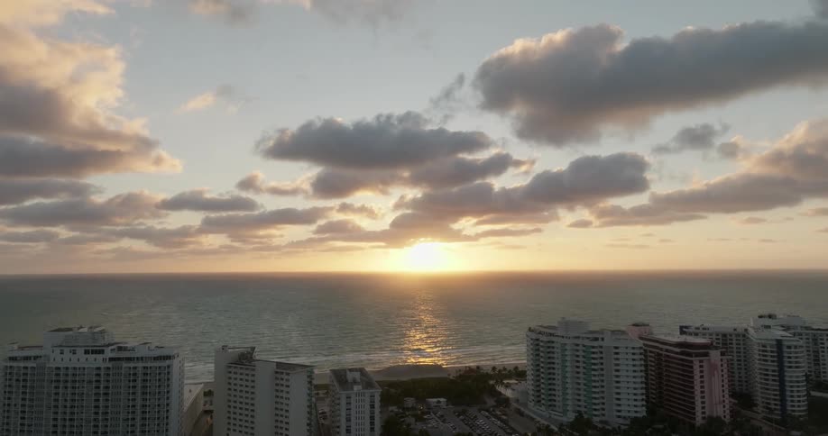 Aerial view of large buildings by the sea with the sun on the horizon South Beach Miami