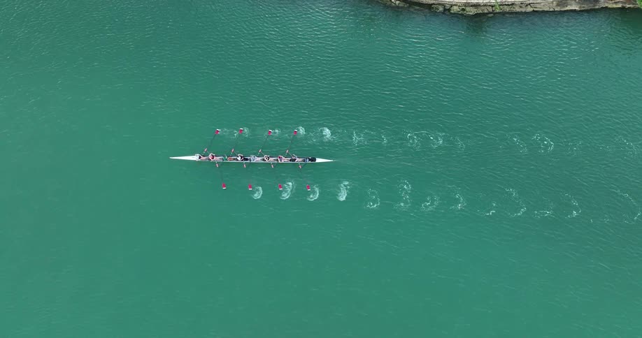 Rowing team in a long narrow boat moving in calm water