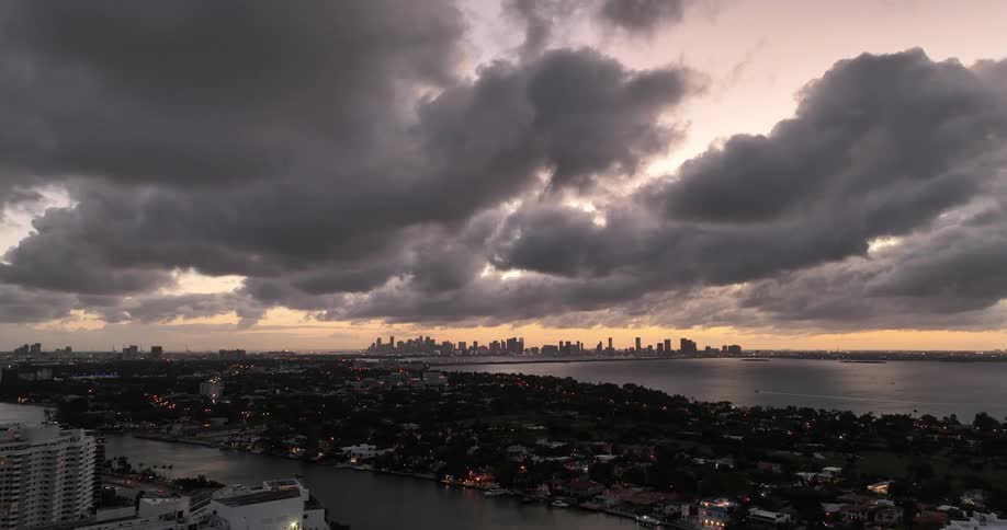 A metropolitan city skyline under cloudy dusk sky with the setting sun
