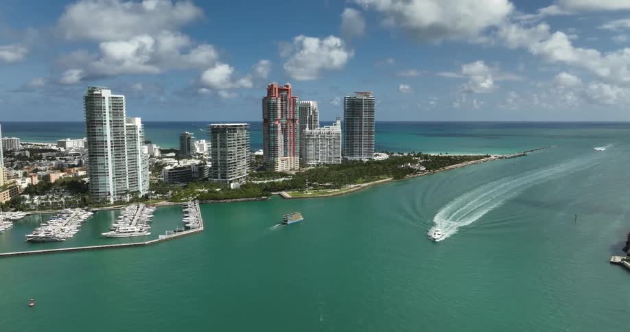 Multiple boats travel atop the ocean water near this coastal cityscape