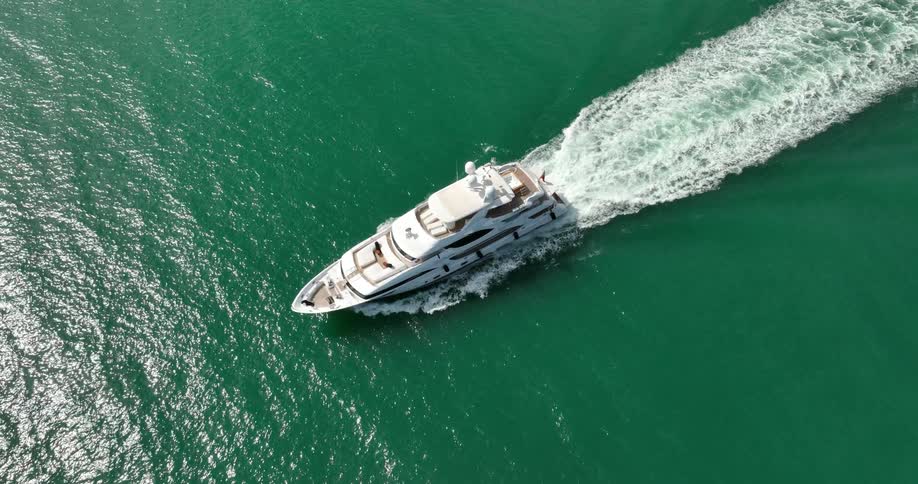 A luxurious white yacht travels across the ocean on a sunny day