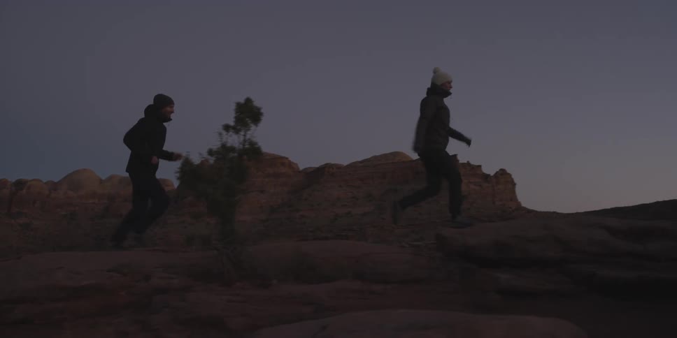 Two men hiking up bald rocks in wilderness at dusk