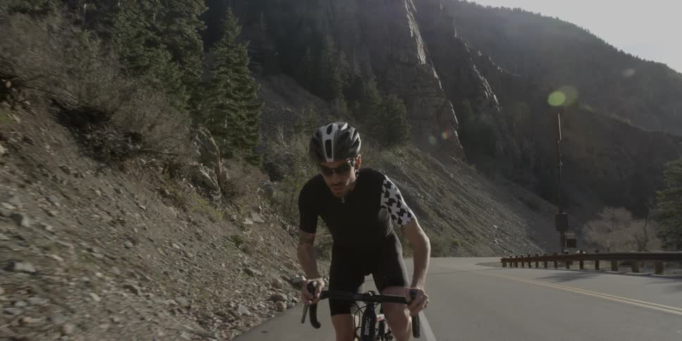 Cyclist pedaling up an inclined paved road