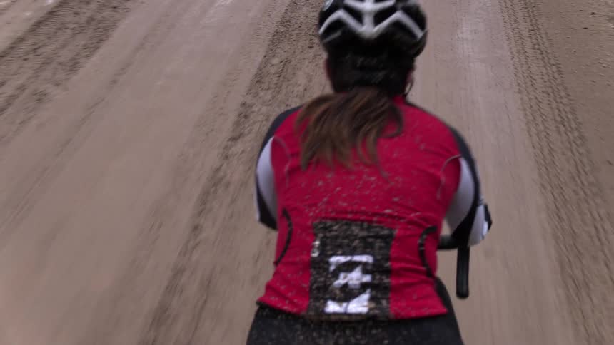 A woman is riding her mountain bike down a dirt road