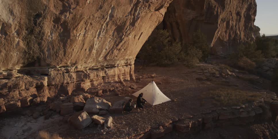 Two people hanging out near their tent along the rock cliffs