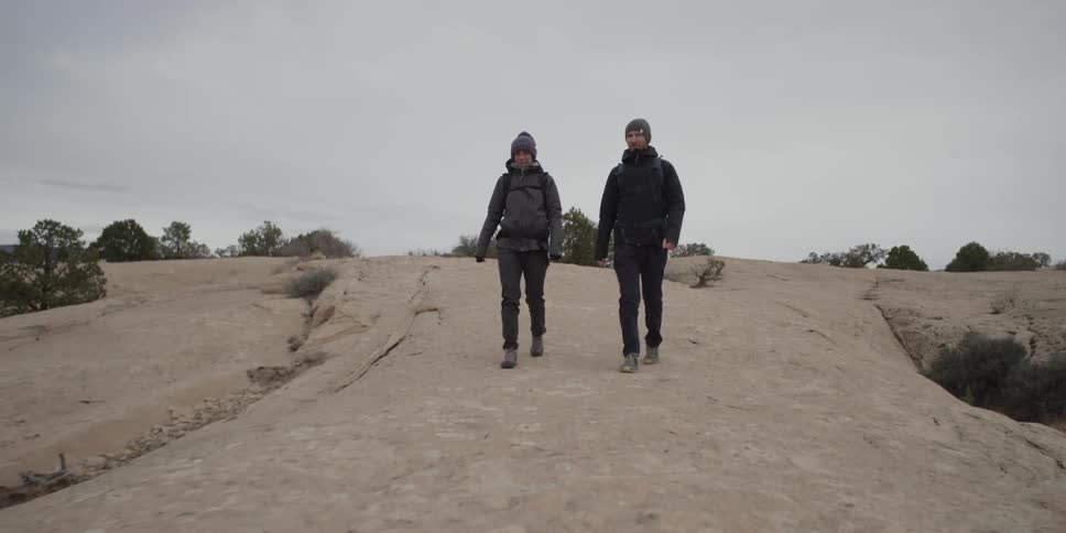 A man and woman are hiking on a cloudy day