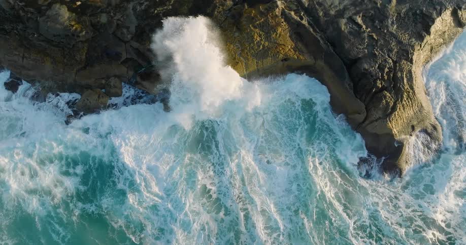 Strong foamy waves crashing onto the rocky shore