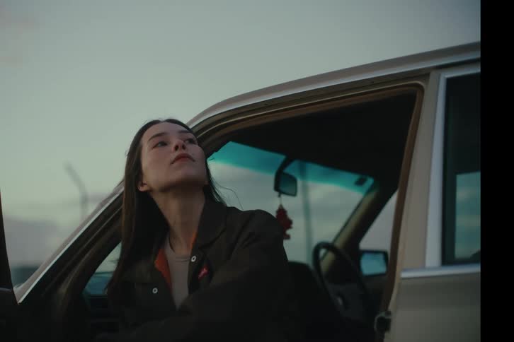 Young woman sitting in the front seat of a car looking at the sky
