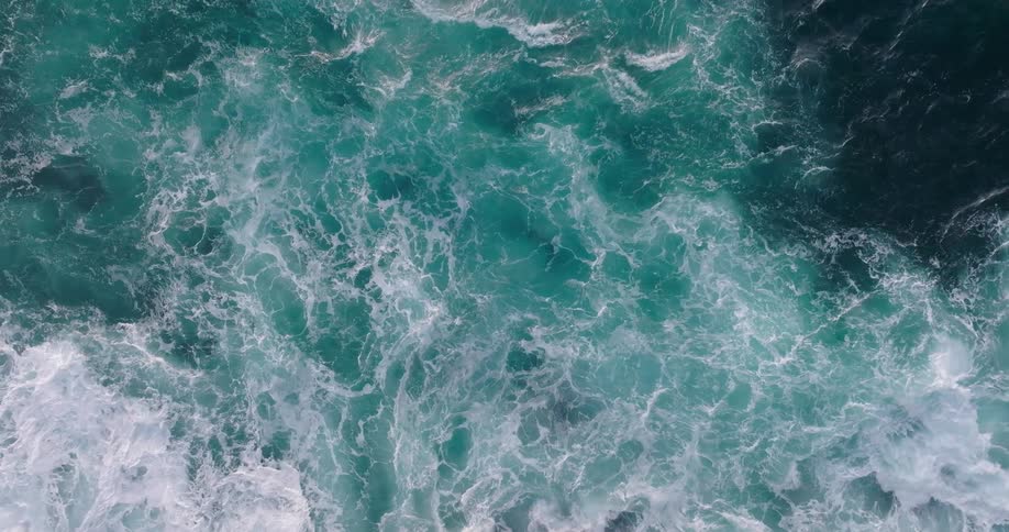 Aerial view of turbulent ocean waters with varying shades of blue and white foam