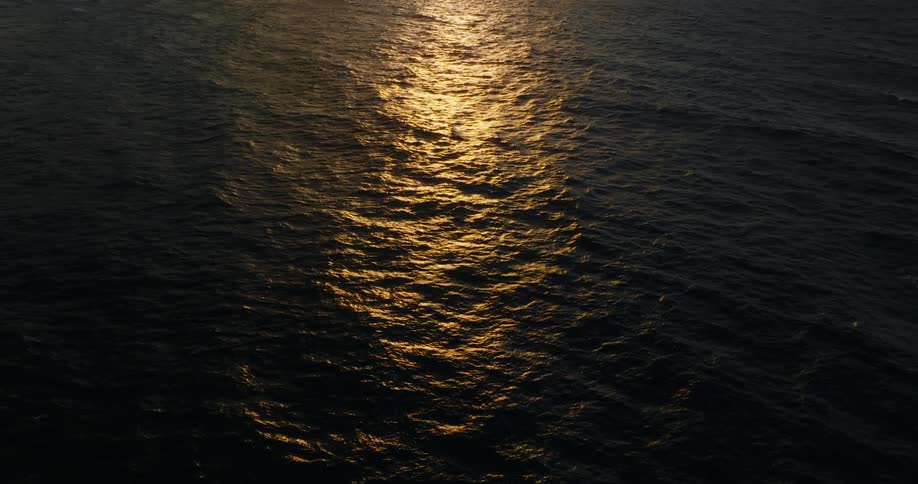 Golden reflection of the sun spreads across the rippled surface of the sea