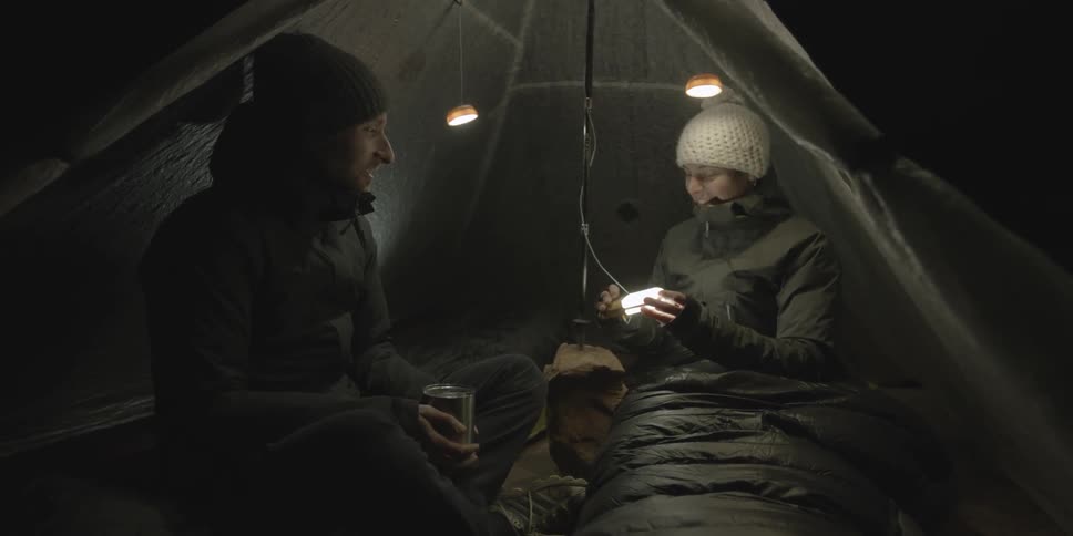 Woman providing light  inside the tent for her and her  male friend